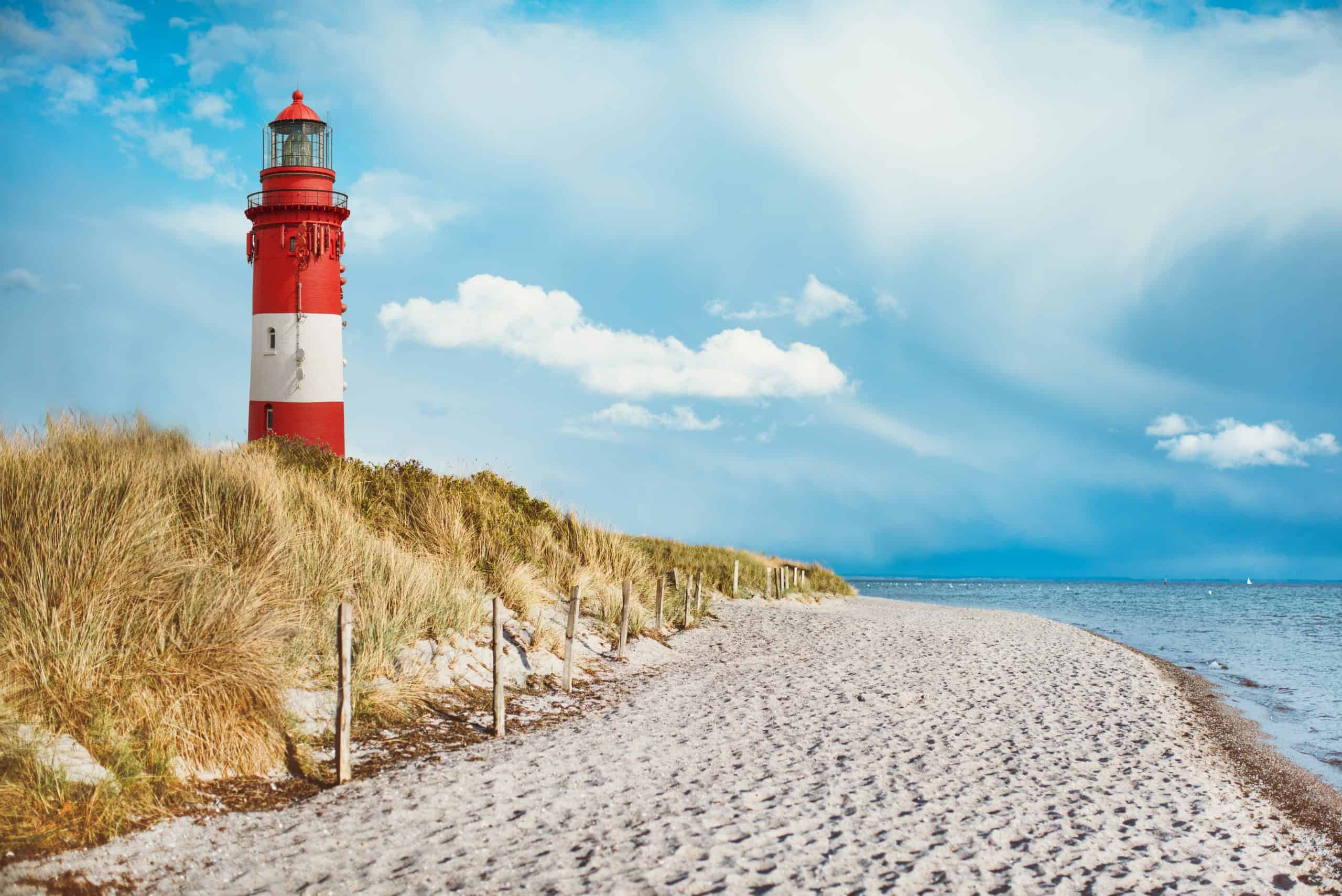 Lighthouse on the beach of an island with sand and water and clouds Urlaubsbild